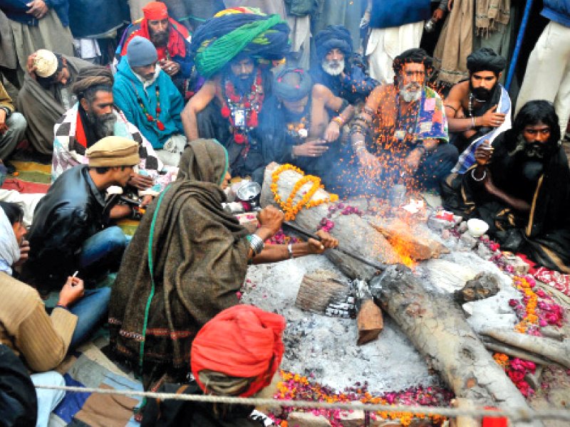 Devotees sit around a fire. PHOTO: MEHMOOD QURESHI/EXPRESS