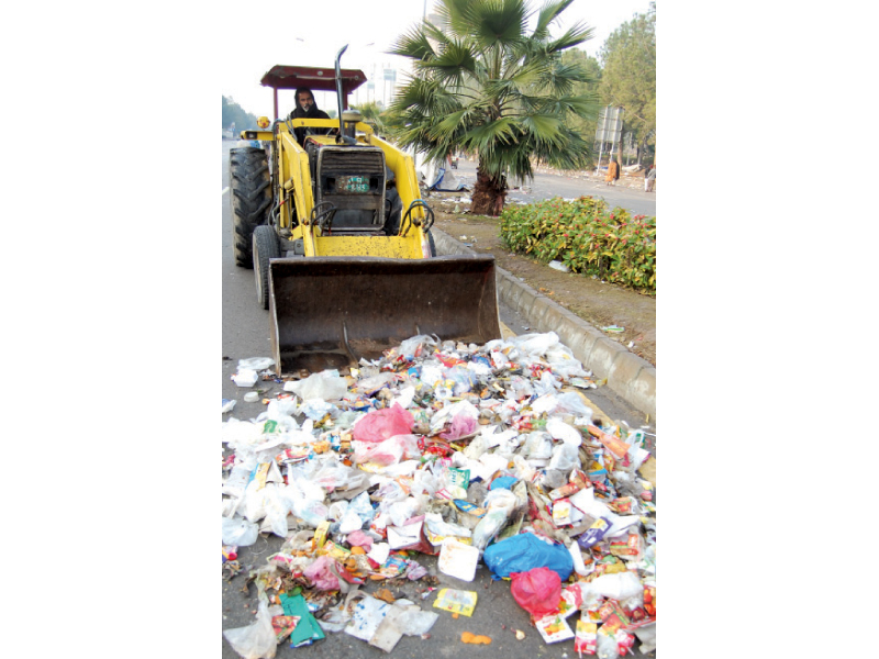 A crane lifts a container blocking access to the Red Zone(top); a bulldozer collects trash on the road. PHOTO: MUHAMMAD JAVAID/EXPRESS