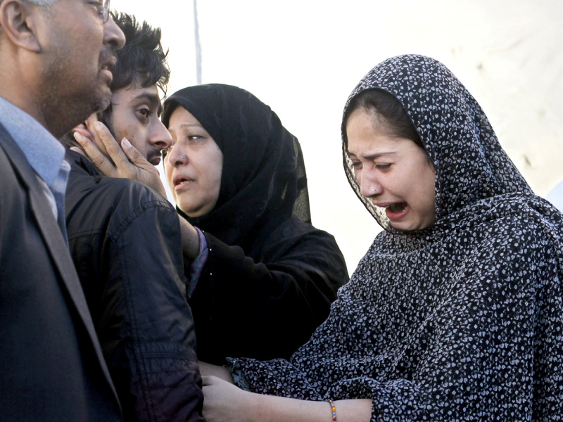 Family members mourn the death of their relatives in Karachi. PHOTO: REUTERS