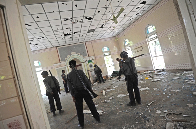 Myanmar police inspect a damages mosque at a village near Oakkan town. PHOTO: AFP