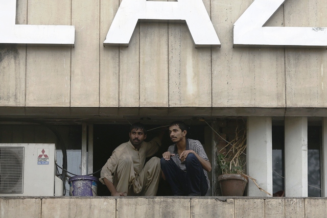Two men wait to be saved from a burning building in central Lahore May 9, 2013. Fire erupted on the seventh floor of the LDA plaza in Lahore. PHOTO: REUTERS