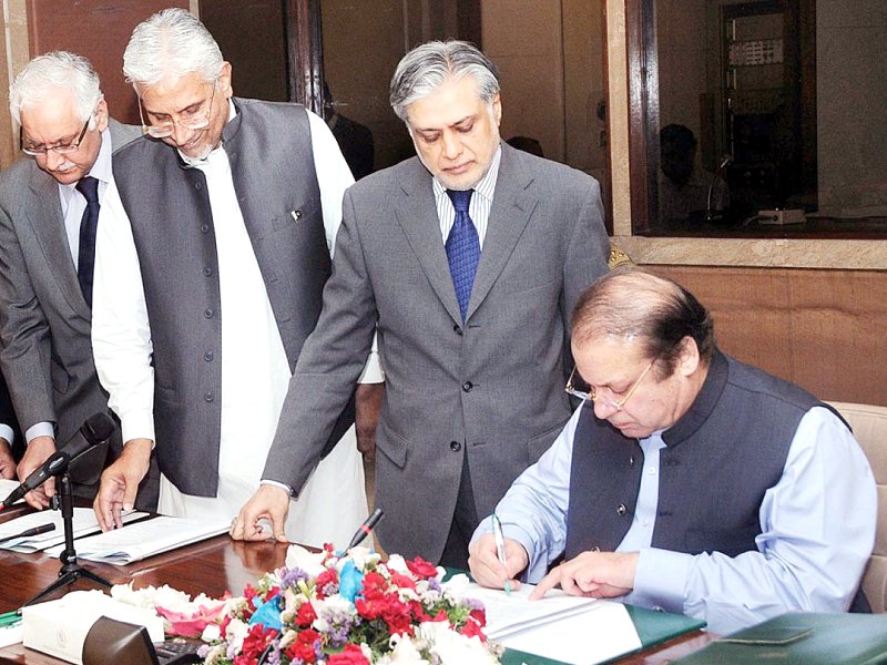 Prime Nawaz Sharif signs the budget document as Finance Minister Ishaq Dar looks on. PHOTO: APP