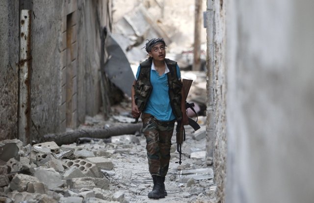 A member of the Free Syrian Army walks with his weapon in a damaged street filled with debris in Aleppo's Karm al Jabal district, June 3, 2013. PHOTO: REUTERS/FILE