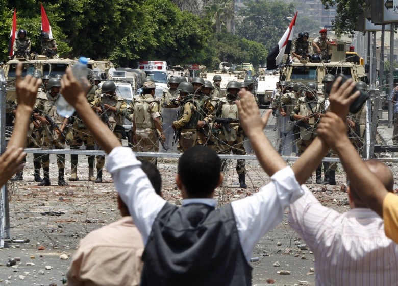 Members of the Muslim Brotherhood and supporters of deposed Egyptian President Mohamed Mursi shout slogans in front of army soldiers at Republican Guard headquarters in Nasr City, in the suburb of Cairo July 8, 2013. PHOTO: REUTERS