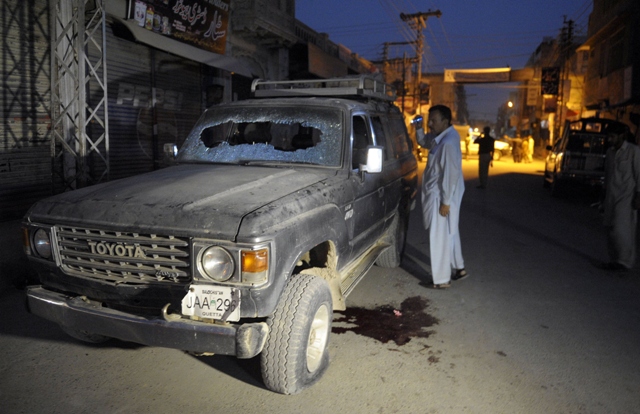 A Pakistani plainclothes police officer looks at a bullet-riddled vehicle after an attack by gunmen in Quetta on July 15, 2013. PHOTO: AFP