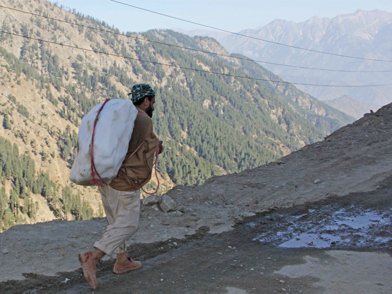 A man carries a slab of ice to be sold to dealers. PHOTO: FAZAL KHALIQ/EXPRESS