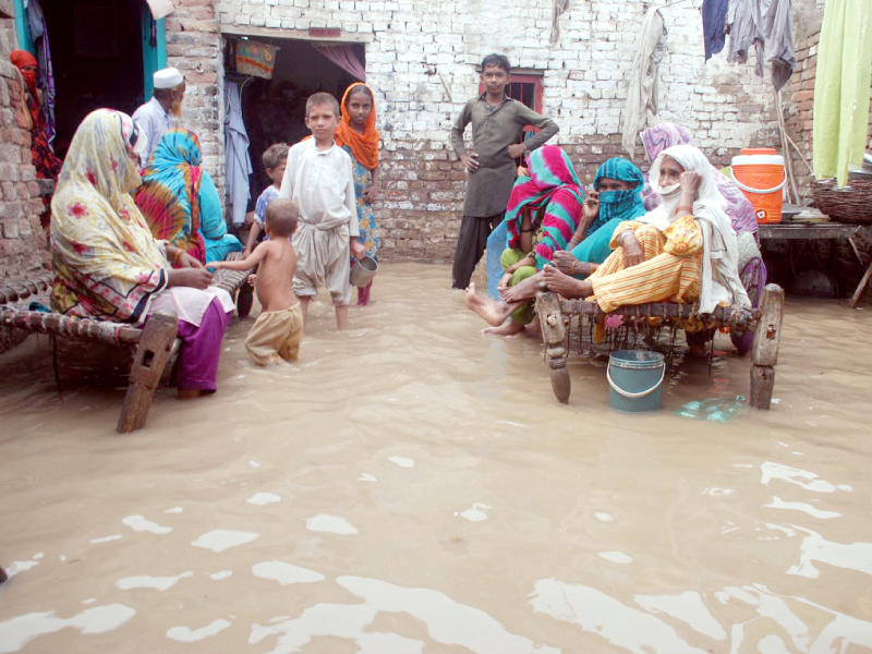 Residents of Micro Colony in Sukkur sit on charpoys after rainwater entered their homes on Saturday. PHOTO: EXPRESS/NAEEM AHMED GHOURI