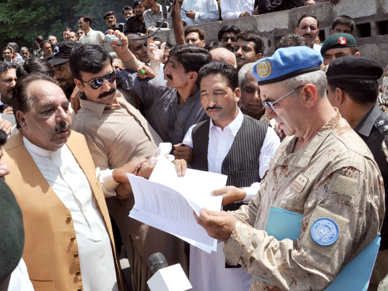 Azad Jammu and Kashmir’s Prime Minister Chaudhry Abdul Majeed hands a memorandum to UN officials in Muzaffarabad. PHOTO: AFP