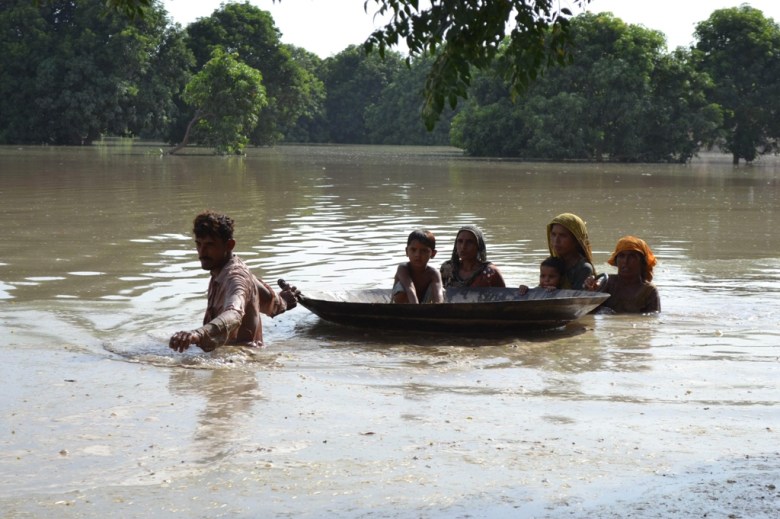 Pakistani villagers wade through floodwaters on the outskirts of Multan on August 21, 2013. PHOTO: AFP