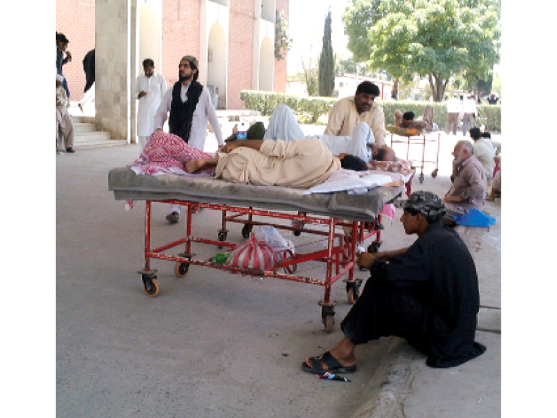 Muhammad Shabbir photographed on Tuesday, has been on this stretcher since Monday afternoon. Less serious cases can be seen outside. PHOTO: SEHRISH WASIF/EXPRESS