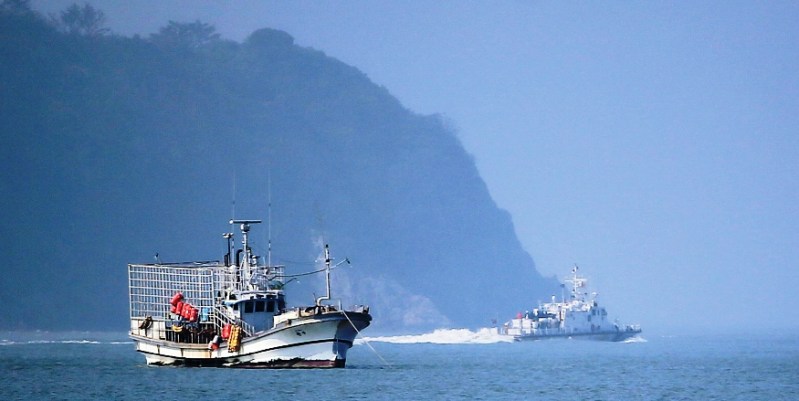 A coastguard boat (R) passes behind a fishing vessel off the coast of the southern island of Jindo, near the site of the Sewol ferry, on May 12, 2014. PHOTO: AFP