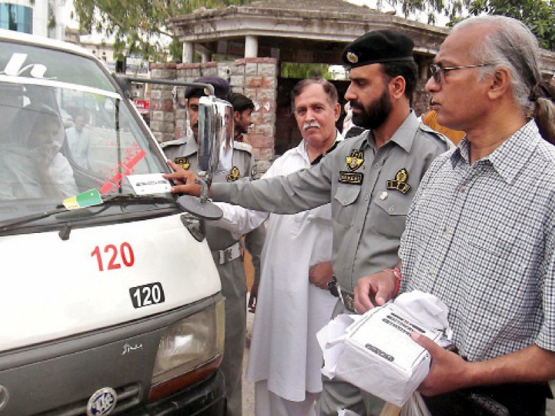 A police official pastes the sticker on a van. PHOTO: MUHAMMAD JAVAID/ EXPRESS