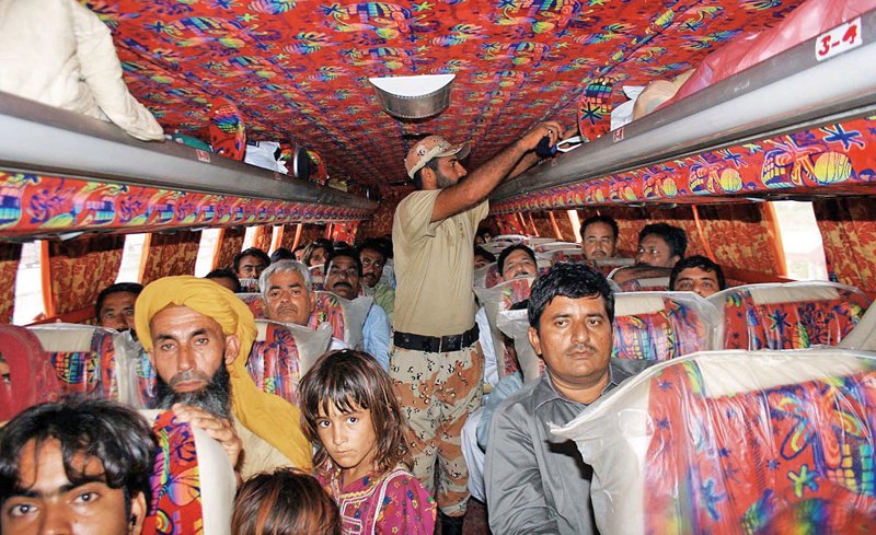 A Rangers official checks the identification documents and luggage of the occupants of a passenger bus at the Super Highway on Monday. Rangers personnel conduct these security checks at all entry and exit points of the city to curb the influx of militants and illegal immigrants into the city. PHOTO: ONLINE