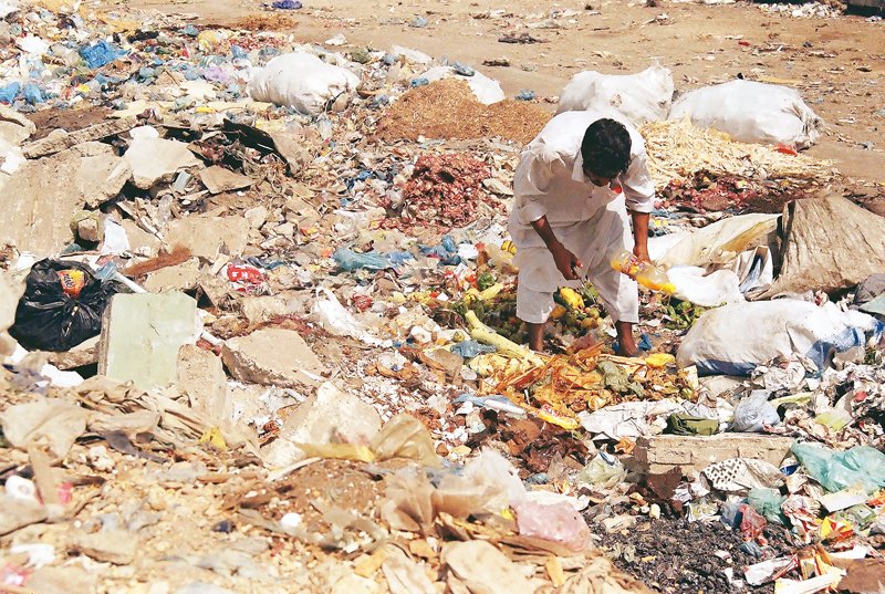 In this file photo, a man forages for something to eat in a garbage dump in Karachi. PHOTO: ARIF SOOMRO