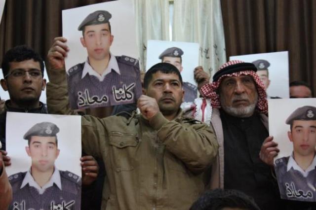 Relatives of IS captive Jordanian pilot Muath al-Kasaesbeh hold his poster as they take part in a rally in his support at the family's headquarters in the city of Karak. PHOTO: REUTERS
