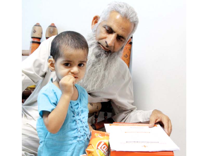 A child with a cochlear implant in her ear eats her snack. DUHS treated 12 other such children last month. They had hearing disability but now, thanks to the implants, they can hear and are ready for speech therapy. PHOTO: AYSHA SALEEM/EXPRESS