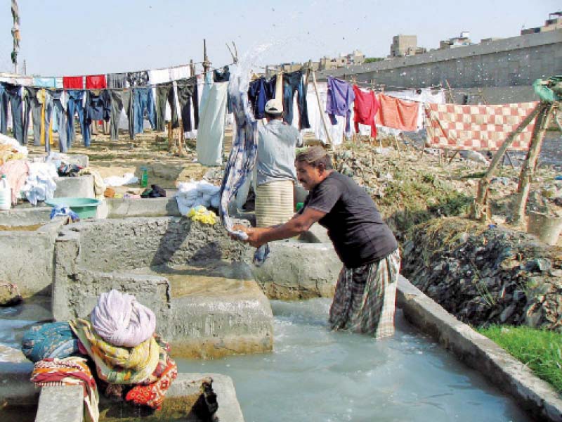 A dhobi washes clothes at the Dhobi Ghat situated under the Teen Hatti Bridge. PHOTO: FILE
