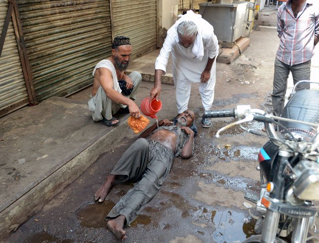 A resident helps a heatstroke victim at a market area during a heatwave in Karachi on June 23, 2015. PHOTO: AFP