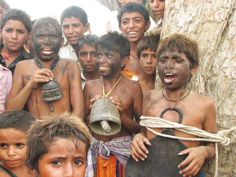 Faces of orphans are blackened and an animal’s bell and pan are tied around their necks. PHOTO : GULSHER PANHWER