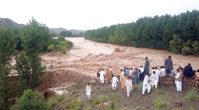 People watch Salyaza stream flow in full flood in Zhob district. PHOTO: BANARAS KHAN/EXPRESS