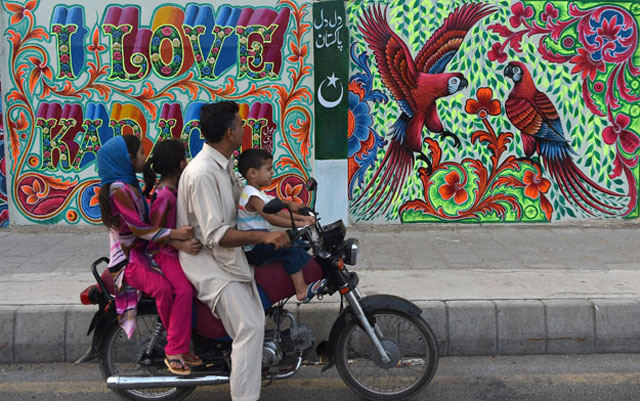 A Pakistani family looks at art work on a wall on a commercial street in the southern port city of Karachi. PHOTO: AFP