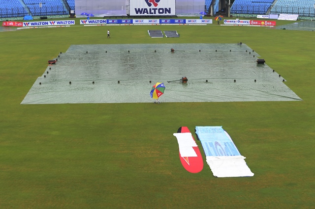 Cricket officials walk across the playing surface as the rain delayed play on the fourth day of the first cricket Test match between Bangladesh and South Africa. PHOTO: AFP