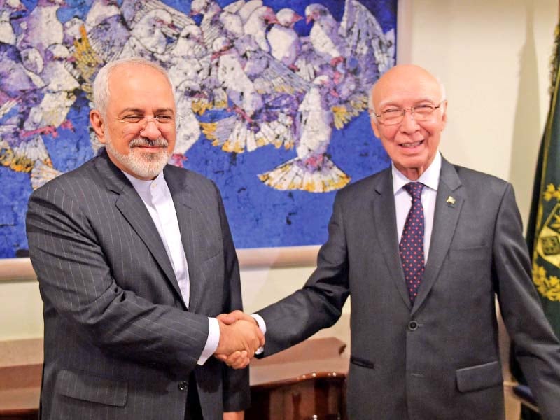 Sartaj Aziz shakes hands with Javad Zarif at the foreign ministry in Islamabad. PHOTO: AFP