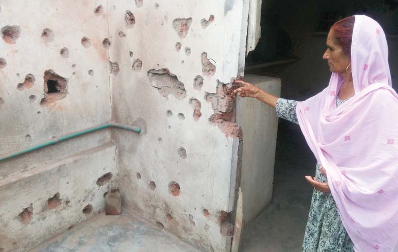 An old woman shows her house damaged by Indian shelling. PHOTO: INP