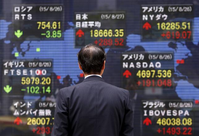 A pedestrian looks at an electronic board showing the stock market indices of various countries outside a brokerage in Tokyo, Japan, August 27, 2015. PHOTO: REUTERS