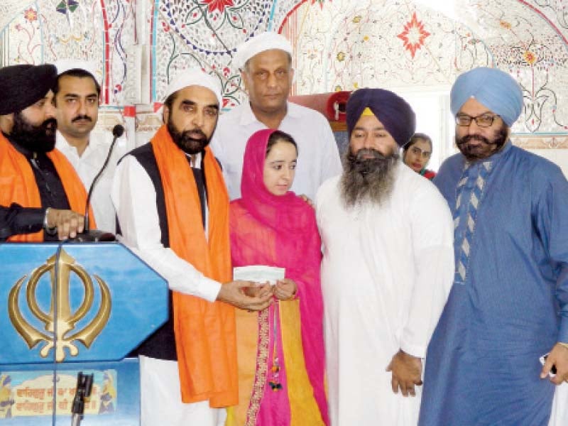 Evacuee Trust Board Chairperson Siddiqul Farooq presents a cheque to the promising Sikh student. PHOTO: EXPRESS