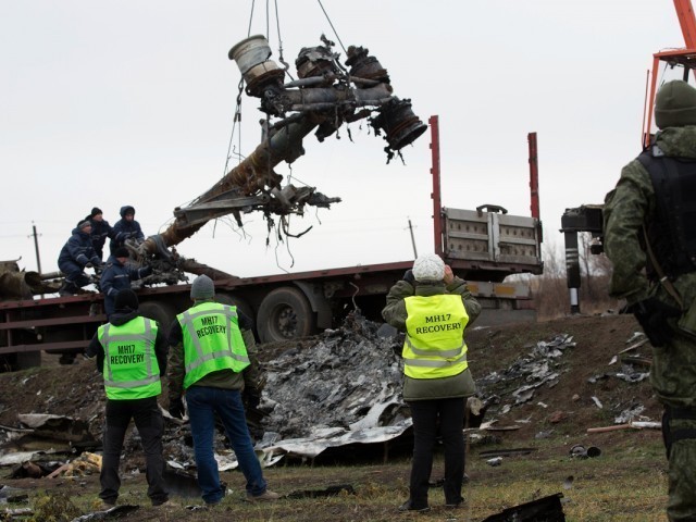 Members of the Dutch export team watch as parts of the wreckage of the Malaysia Airlines Flight MH17 are removed and loaded on a truck at the crash site near the village of Grabove in eastern Ukraine, on November 16 2014. PHOTO: AFP