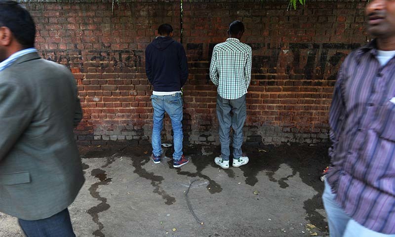 Indian men urinate on a wall at a roadside in New Delhi. PHOTO: AFP
