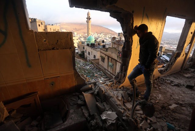 A Palestinianm man looks at the rubble of the house of Ragheb Ahmad Mohammad Alawi, a Palestinian accused of masterminding the killing of a Jewish Israeli settler couple in the Itmar settlement on October 1, after it was destroyed by Israeli authorities in the West Bank city of Nablus early in the morning of December 3, 2015. PHOTO: AFP