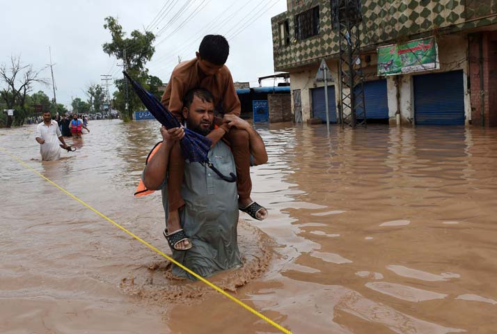 People walk through a flooded area of Peshawar on July 26, 2015. PHOTO: AFP