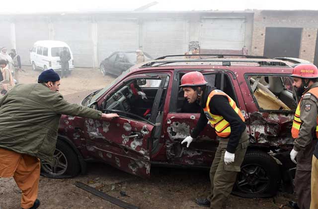 Rescue workers search a damaged vehicle after a roadside bomb explosion in Peshawar on January 24, 2016. PHOTO: AFP