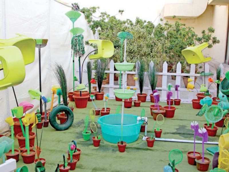An art installation shows a garden made of plastic utensils, toilet brushes and discarded shoes.