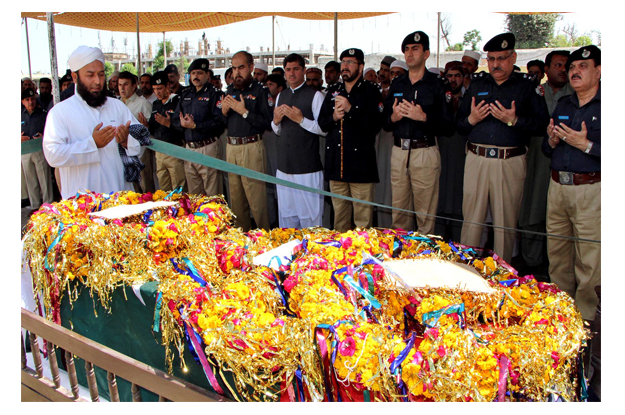 Police officials and others are offering Fateha during the funeral of ASI Qaiser Shah at Yakatoot. PHOTO: INP