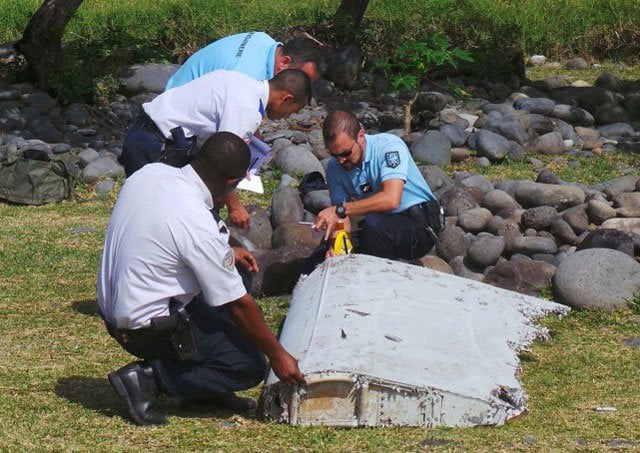 French gendarmes and police inspecting a large piece of plane debris which was found on the beach in Saint-Andre, on the French Indian Ocean island of La Reunion, July 29, 2015. PHOTO: REUTERS