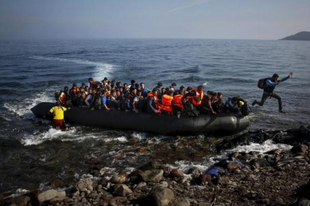 An Afghan migrant jumps off an overcrowded raft onto a beach at a Greek island PHOTO: REUTERS