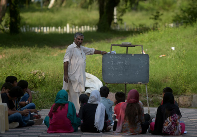 In this photograph taken on August 30, 2016, Muhammad Ayub teaches pupils at a makeshift school in a park in Islamabad. PHOTO: AFP