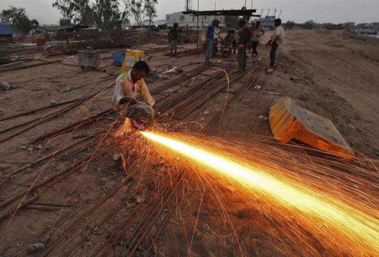 A labourer cuts an iron rod at the construction site of a flyover on the outskirts of the western Indian city of Ahmedabad. PHOTO: REUTERS