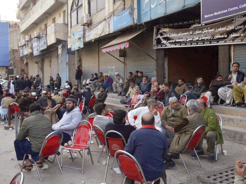 Owners, employees of medical stores sit outside their shops. PHOTO: ZAFAR ASLAM/EXPRESS