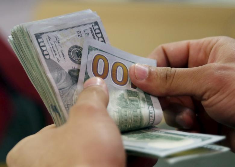 A customer counts his US dollar money in a bank. PHOTO:REUTERS