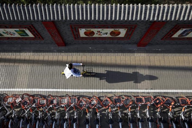 A woman rides an Ofo's shared bike past Mobike's shared bikes in Beijing's central business area, China April 21, 2017. Picture taken April 21, 2017. PHOTO: REUTERS