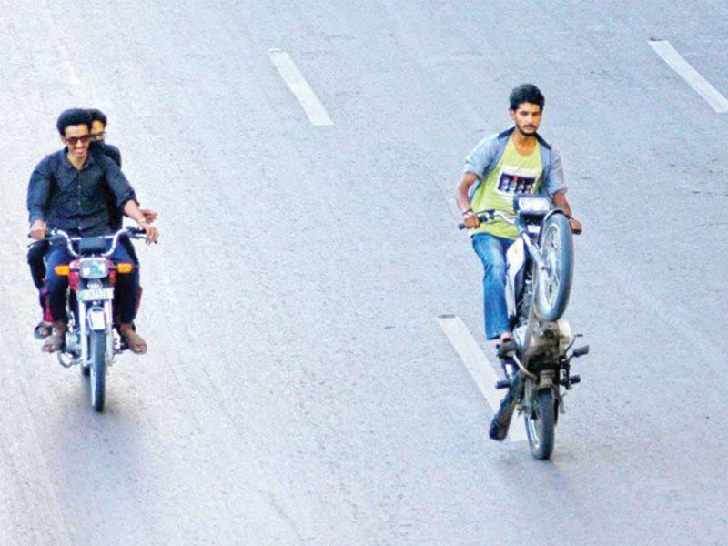 A rider one-wheels on his motorbike on Benazir Bhutto Shaheed Road near New Town Police Station. PHOTO: WASEEM IMRAN/EXPRESS