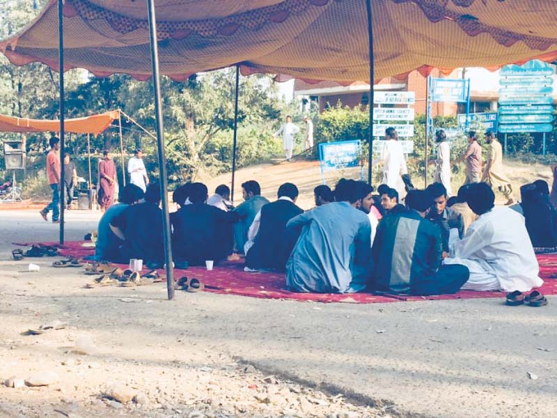 Protesters sit outside the administration block at QAU. PHOTO/ EXPRESS