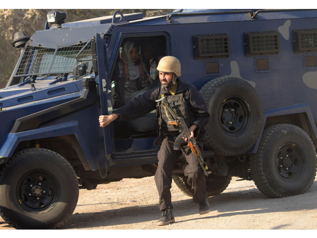 A police commando escorts rescued staff members of an Agriculture Training Institute sit in a armoured vehicle after an attack by Taliban militants in Peshawar on December 1, 2017. PHOTO: AFP