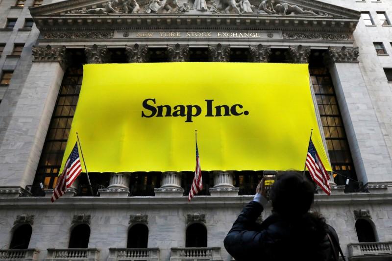 A woman photographs a banner for Snap Inc. on the facade of the New York Stock Exchange (NYSE) on the morning of the company's IPO in New York City, NY, U.S. March 2, 2017. PHOTO: REUTERS