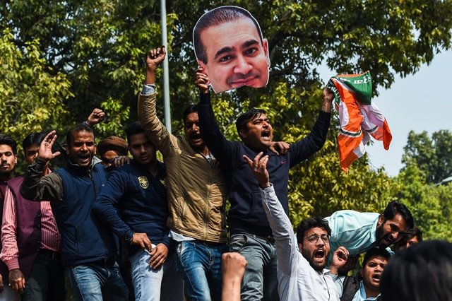 An Indian supporters of the Congress Party keeps his hand on the face of a cut out of billionaire jeweller Nirav Modi during a protest in New Delhi on February 16, 2018.  Indian investigators on February 15 raided the premises of a billionaire jeweller accused of defrauding one of the country's biggest banks. PHOTO: APF