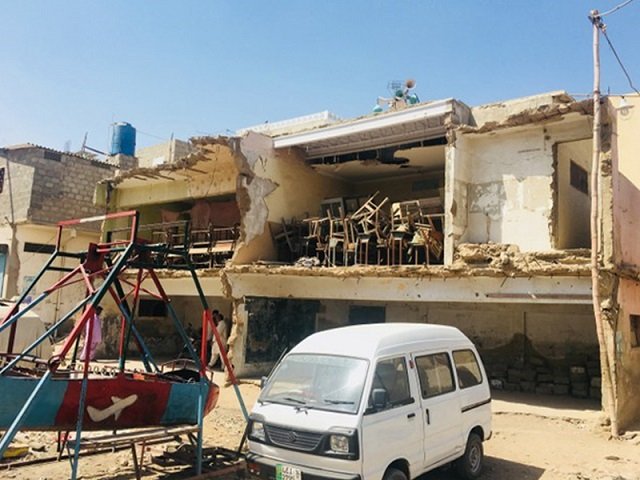 Owing to a dearth of cleaning staff, students are forced to dust their own desks and chairs, as well as, cleaning the floors. Students attend lessons sitting on the floor. PHOTO: EXPRESS